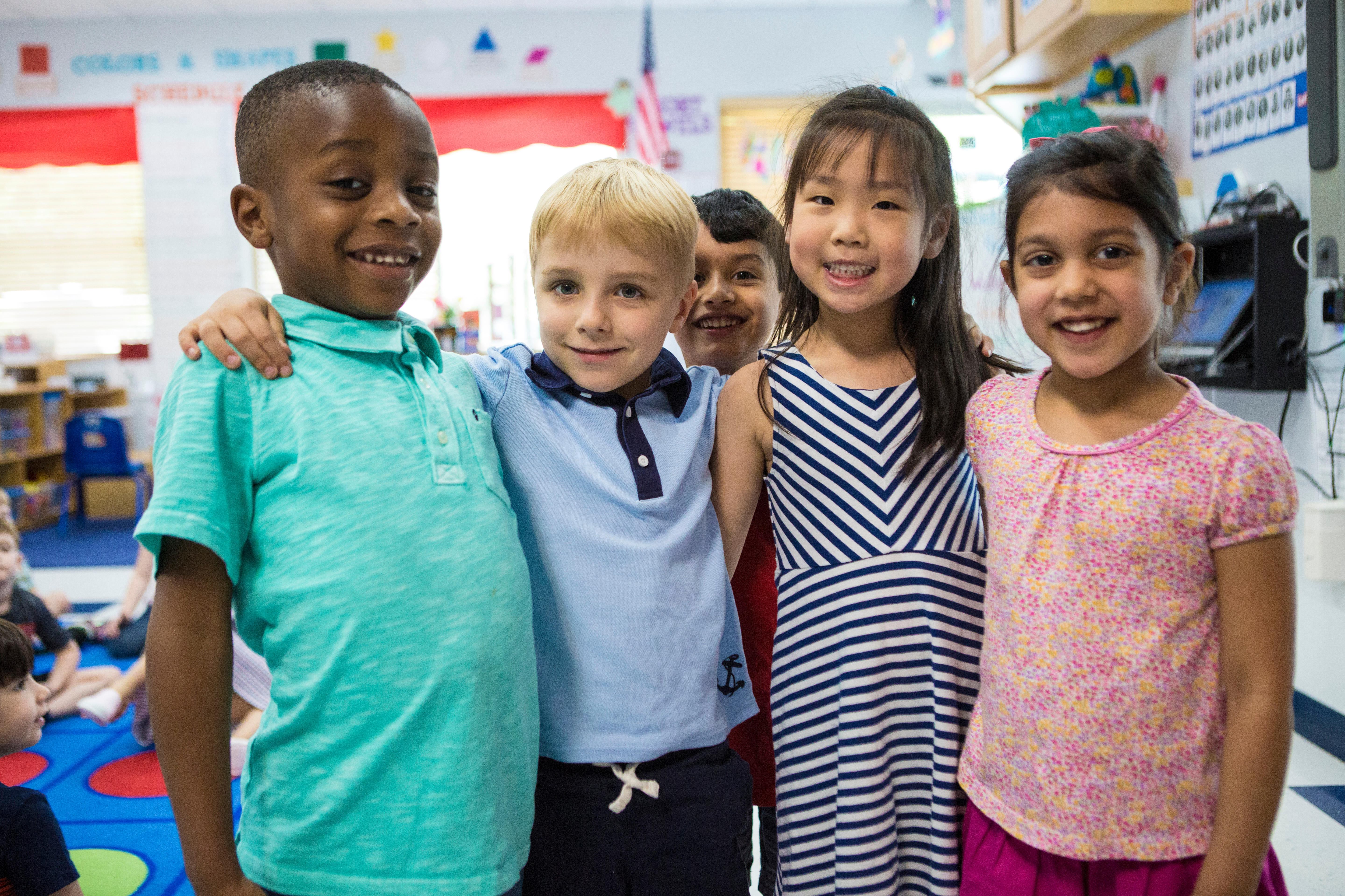 Four children standing together in a classroom