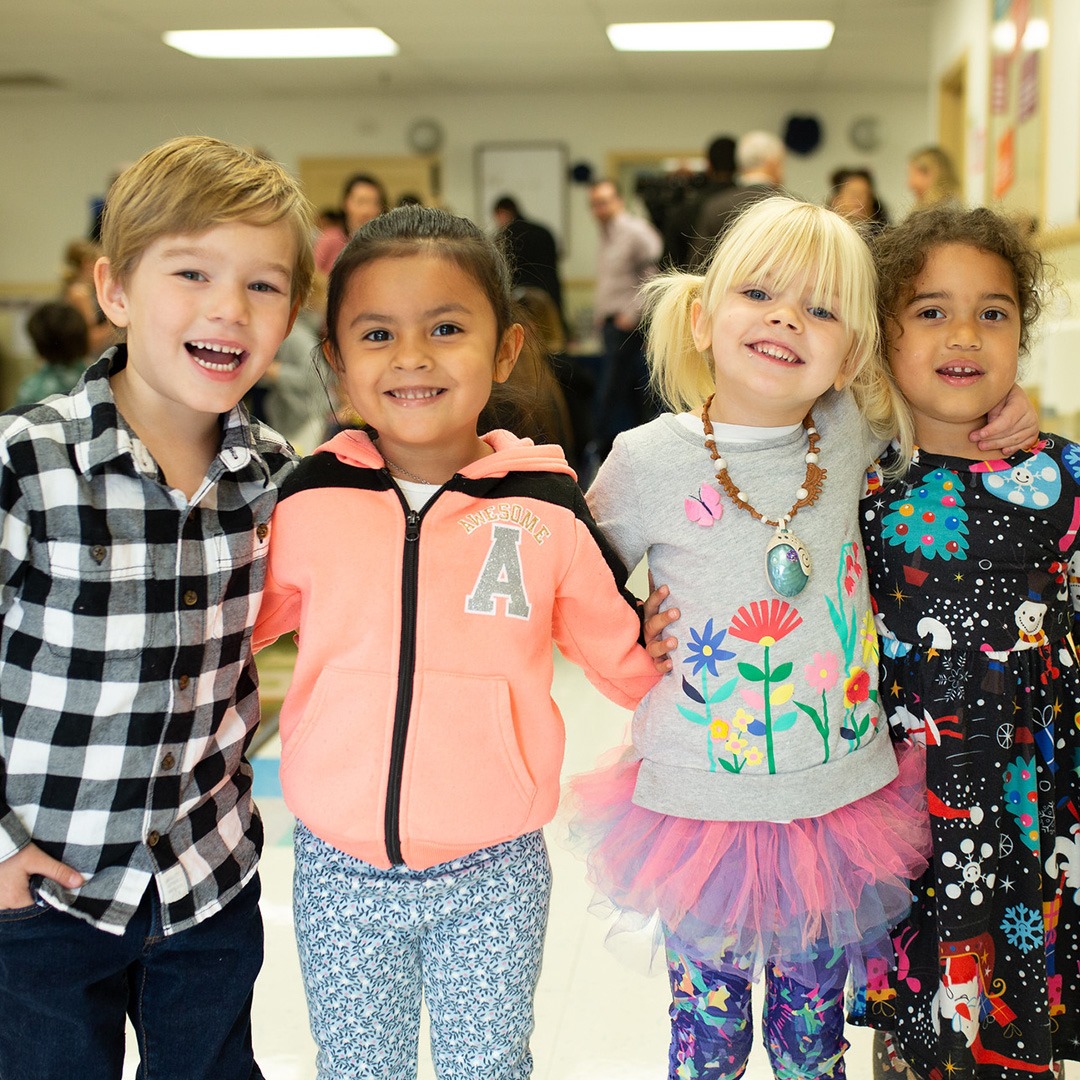 Four children standing together, smiling
