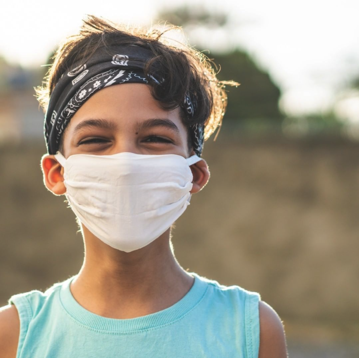Child wearing a white face mask and a bandana