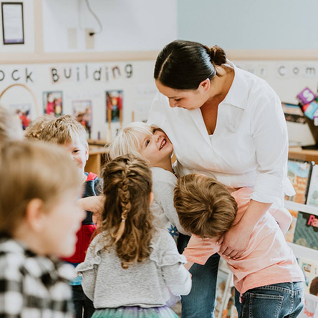 Adult person interacting with multiple children in a classroom