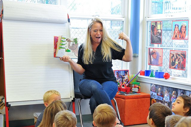 Person reading a book to children in a classroom