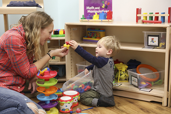 Person and child playing with toys on the floor