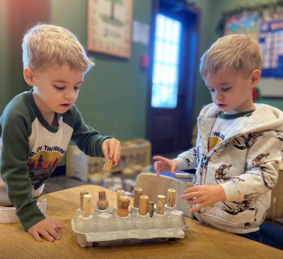 Two children playing with wooden pegs and a pegboard