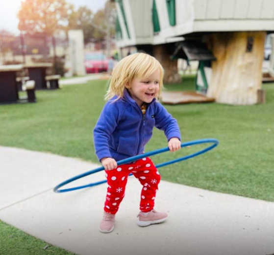 Child playing with a blue hula hoop outdoors