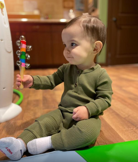 Child sitting on floor holding a colorful rattle