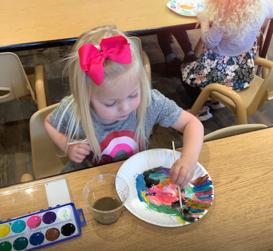 Child painting on a paper plate at a table