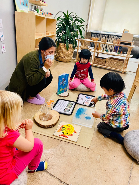 Adult and three children on floor with learning materials
