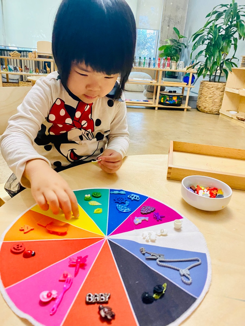 Child playing with a colorful sorting wheel and small objects